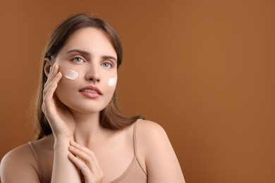 Photo of Beautiful woman with cream on her face against brown background. Space for text