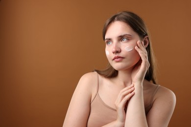 Photo of Beautiful woman with cream on her face against brown background. Space for text