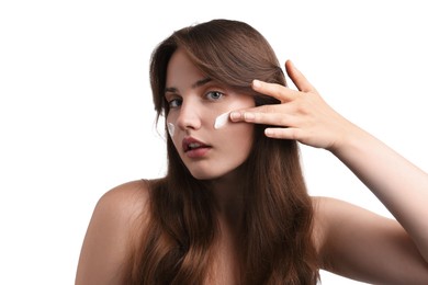 Photo of Beautiful woman applying cream onto her face on white background