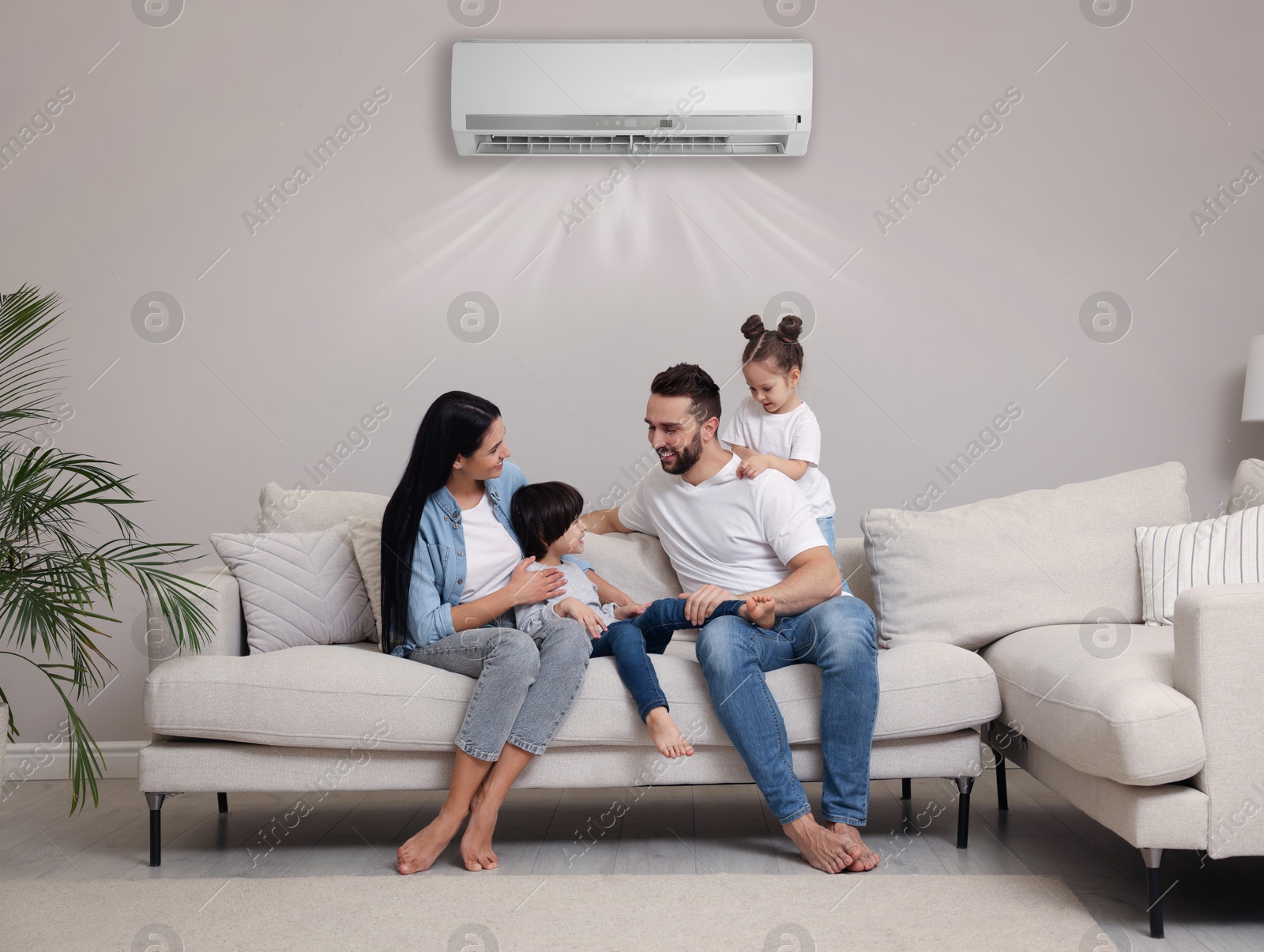 Image of Happy family on sofa in living room. Air conditioner keeping comfortable temperature in room
