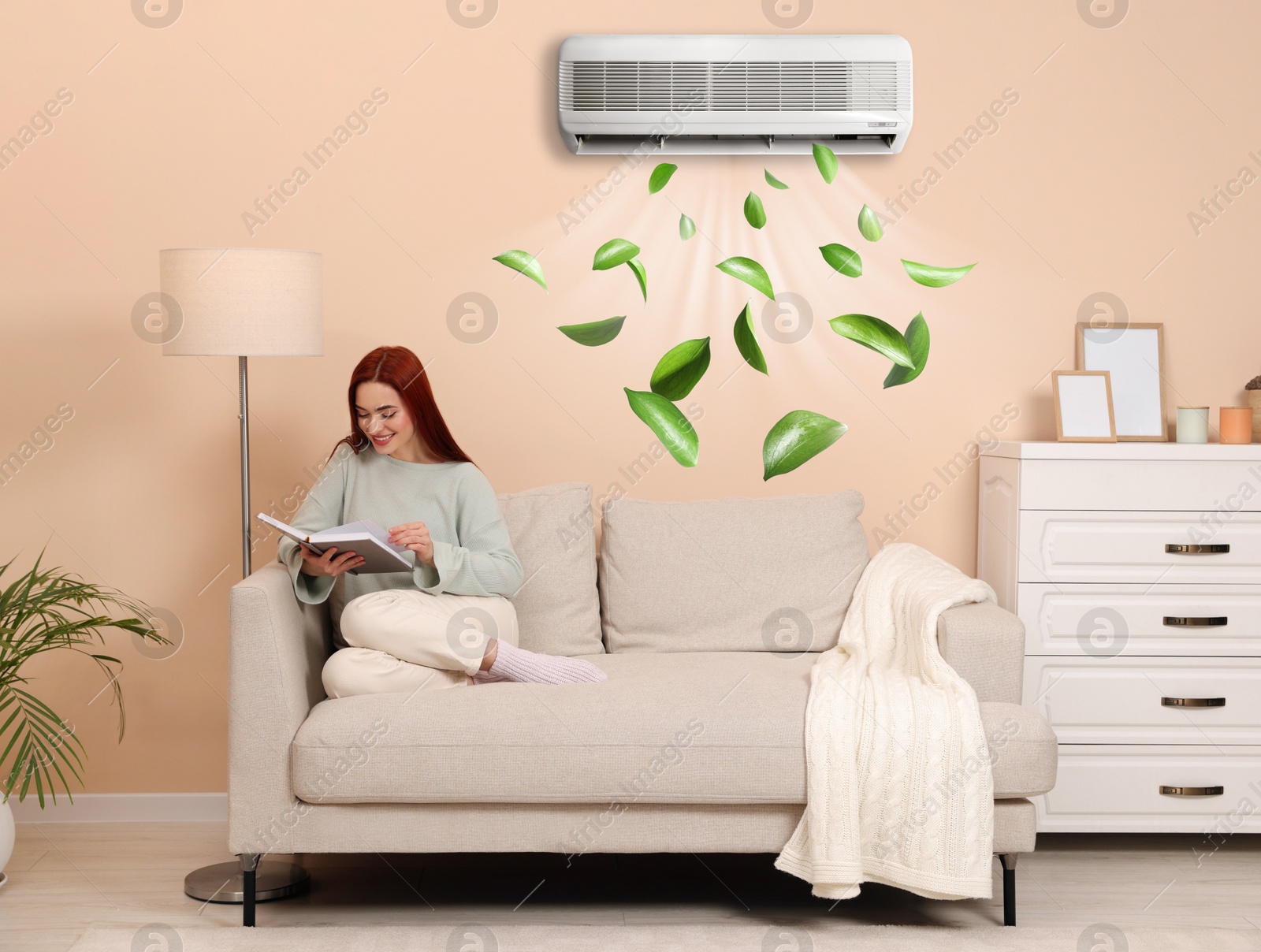 Image of Happy woman reading book at home. Air conditioner keeping comfortable temperature in room