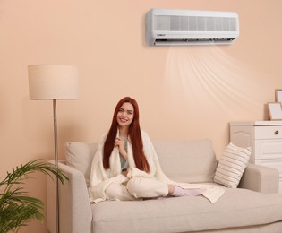 Image of Happy woman on sofa at home. Air conditioner keeping comfortable temperature in room