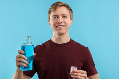 Photo of Man with mouthwash on light blue background. Oral hygiene