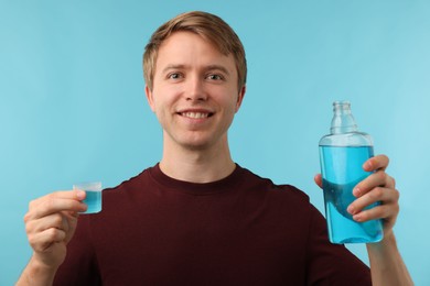 Photo of Man using mouthwash on light blue background. Oral hygiene