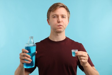 Photo of Man using mouthwash on light blue background. Oral hygiene