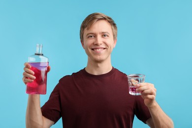 Photo of Man with mouthwash on light blue background. Oral hygiene