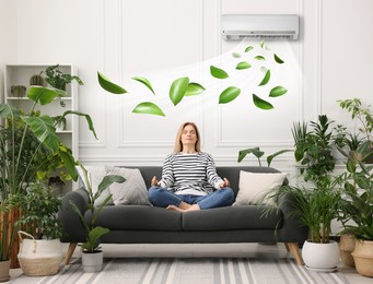 Image of Woman meditating on sofa surrounded by potted houseplants at home. Air conditioner keeping comfortable temperature in room