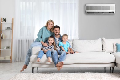 Image of Happy family with children on sofa at home. Air conditioner keeping comfortable temperature in room