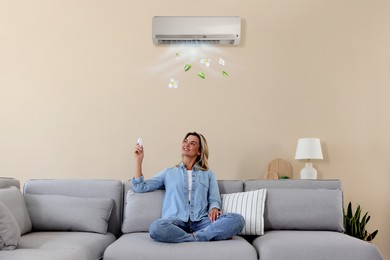 Image of Woman using remote to control air conditioner on sofa at home