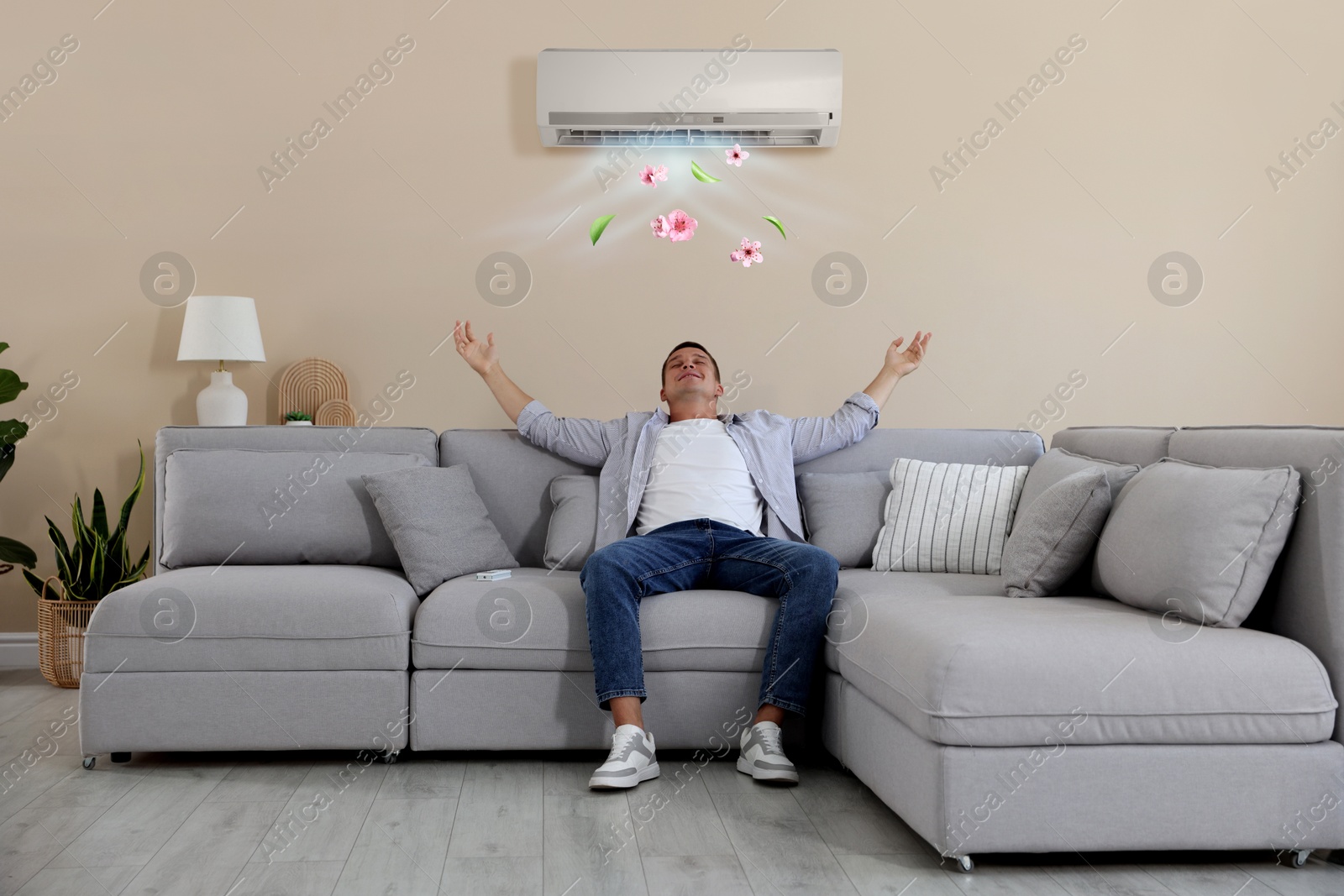 Image of Man enjoying comfortable temperature on sofa in room with air conditioner