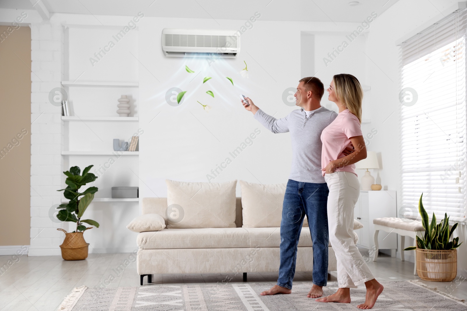 Image of Woman and man using remote to control air conditioner at home