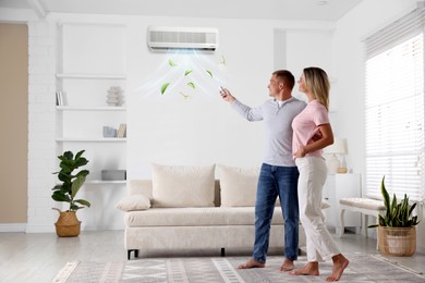 Image of Woman and man using remote to control air conditioner at home