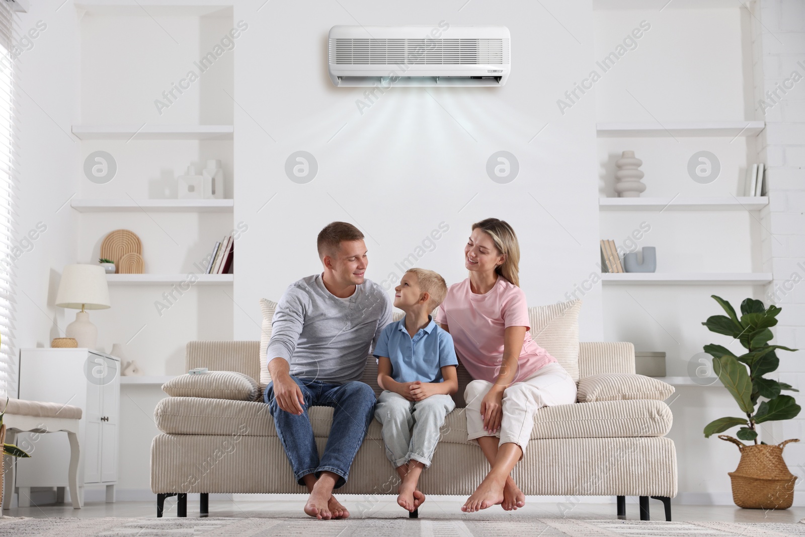 Image of Parents and their son on sofa in room with air conditioner