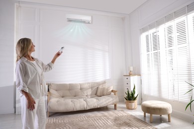 Image of Woman using remote to control air conditioner at home