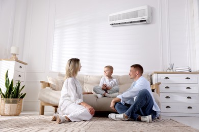 Image of Little boy with air conditioner remote control and his parents at home