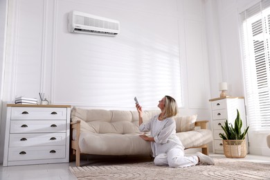 Image of Woman using remote to control air conditioner at home