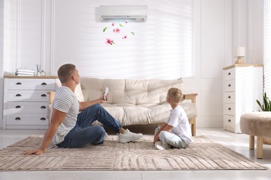 Image of Cute little boy and his father using remote to control air conditioner at home