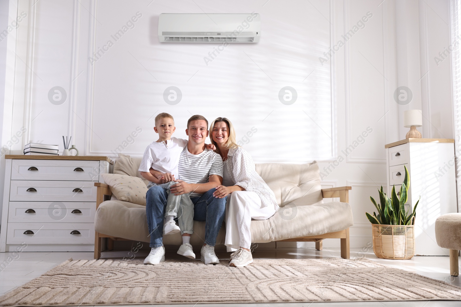 Happy parents and their son on sofa in room with air conditioner Image of Happy parents and their son on sofa in room with air conditioner