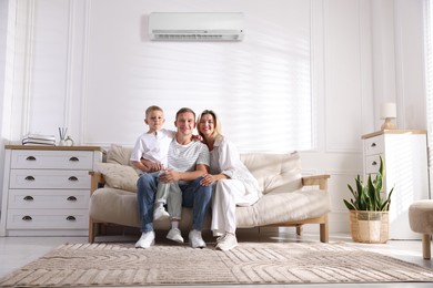 Image of Happy parents and their son on sofa in room with air conditioner