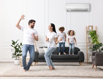 Image of Happy family having fun in living room. Air conditioner keeping comfortable temperature in room