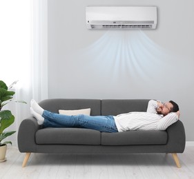Image of Happy man relaxing on sofa at home. Air conditioner keeping comfortable temperature in room