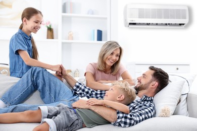 Image of Happy family spending time together on sofa at home. Air conditioner keeping comfortable temperature in room