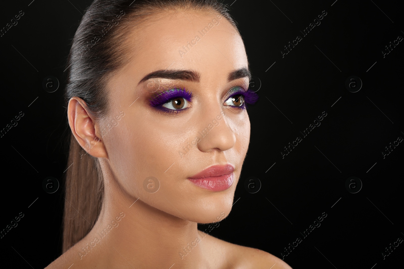 Image of Young woman with beautiful makeup and purple eyelashes against black background, closeup