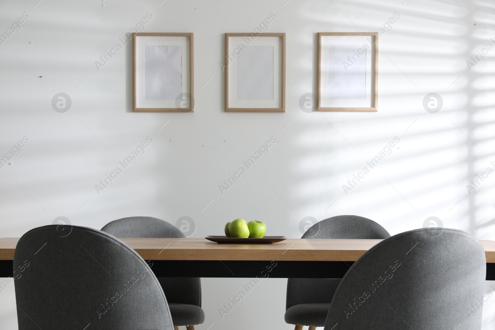 Photo of Plate with apples on wooden table indoors. Stylish interior design