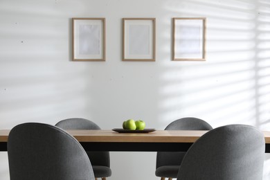 Photo of Plate with apples on wooden table indoors. Stylish interior design
