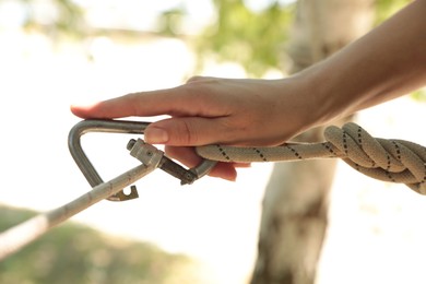 Photo of Woman using screw lock carabiner during training outdoors, closeup