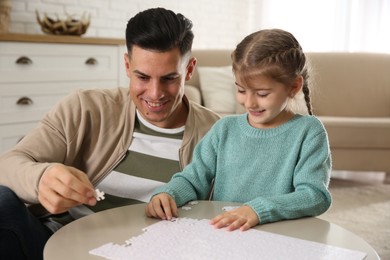 Photo of Happy father and his daughter playing with puzzles at home