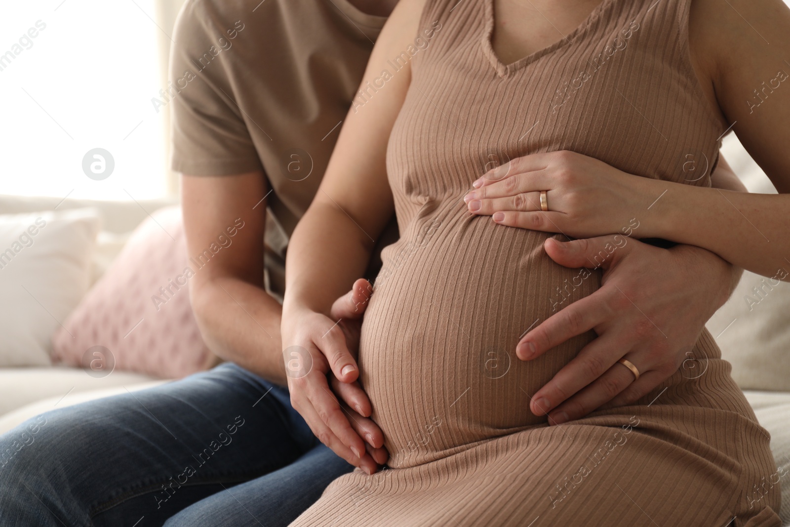 Photo of Man touching his pregnant wife's belly at home, closeup