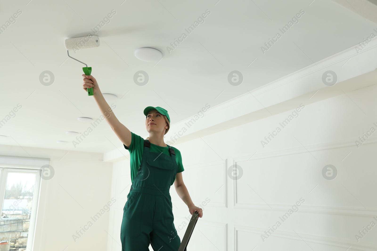 Worker painting ceiling with white dye indoors, space for text Photo of Worker painting ceiling with white dye indoors, space for text