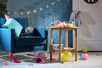 Photo of Armchair and wooden table in messy room after party