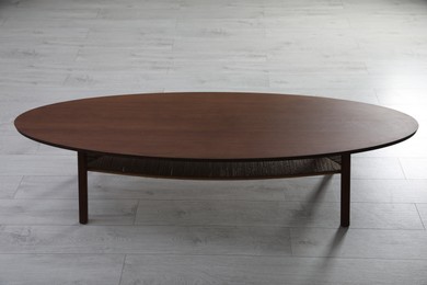 Photo of Empty wooden table on floor indoors. Stylish furniture