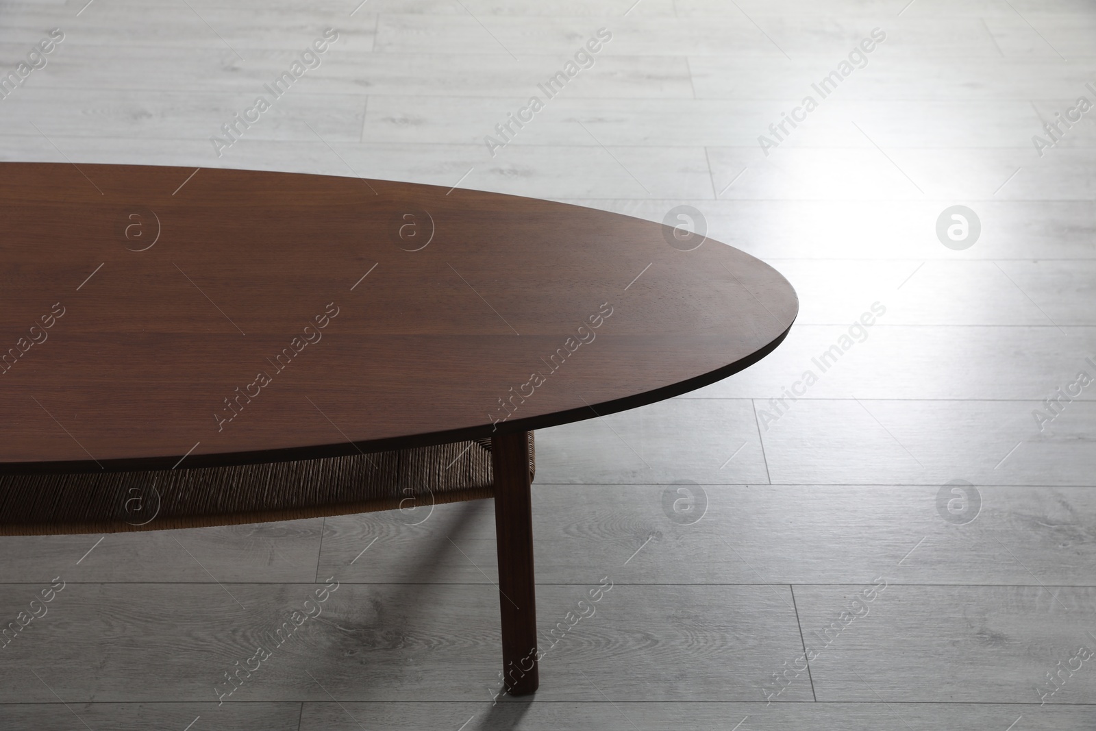 Photo of Empty wooden table on floor indoors. Stylish furniture