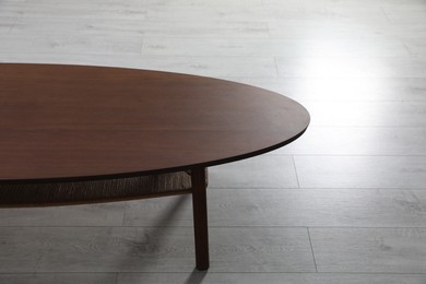 Photo of Empty wooden table on floor indoors. Stylish furniture