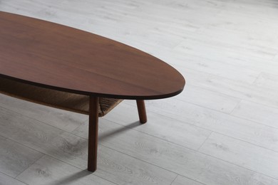 Photo of Empty wooden table on floor indoors. Stylish furniture