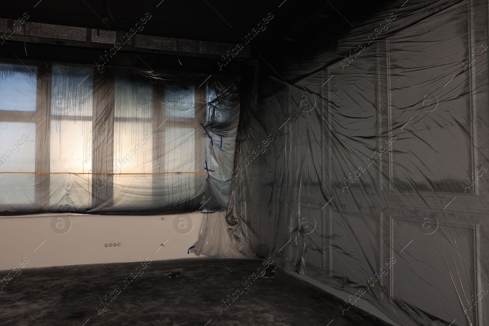 Photo of Windows and wall covered with plastic film in empty room
