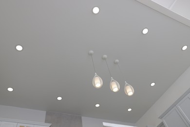 Photo of Ceiling with modern lamps in renovated stylish room, low angle view