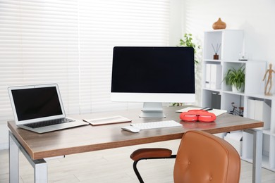 Photo of Modern workplace with computer, laptop, tablet and headphones on wooden desk in office