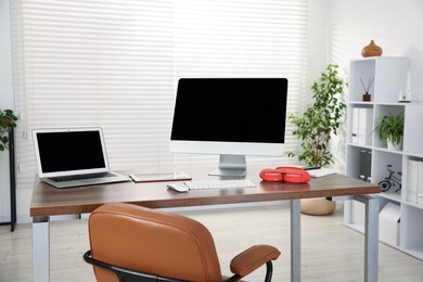 Photo of Modern workplace with computer, laptop, tablet and headphones on wooden desk in office