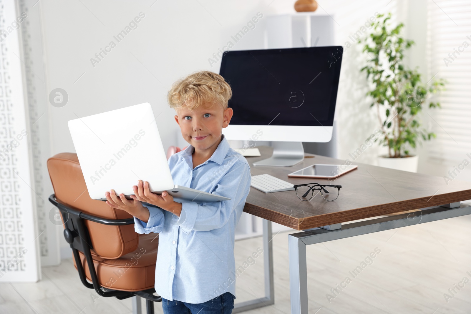 Choice of profession. Little boy pretending to work on laptop in office Photo of Choice of profession. Little boy pretending to work on laptop in office