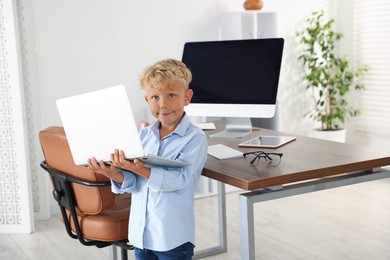Photo of Choice of profession. Little boy pretending to work on laptop in office