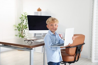 Photo of Choice of profession. Little boy pretending to work on laptop in office