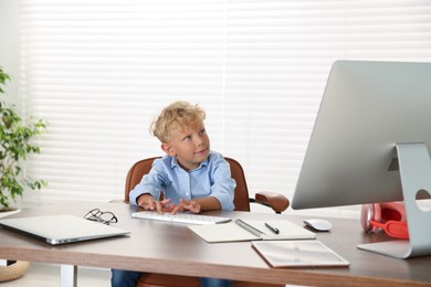 Photo of Choice of profession. Little boy pretending to work on computer in office