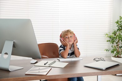 Photo of Choice of profession. Little boy with headphones pretending to work on computer in office