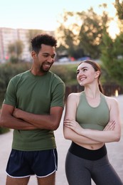 Photo of Smiling runners posing with crossed arms outdoors