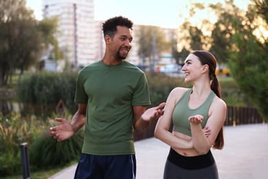 Photo of Smiling runners in sportswear talking outdoors at morning