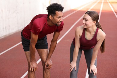 Photo of Smiling couple resting after run at stadium